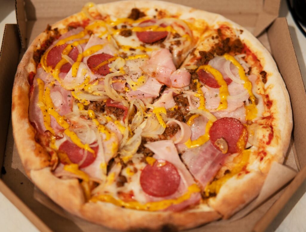 pexels-photo-6151210 Mouthwatering pizza with pepperoni, melted cheese, and vibrant toppings in an open box.